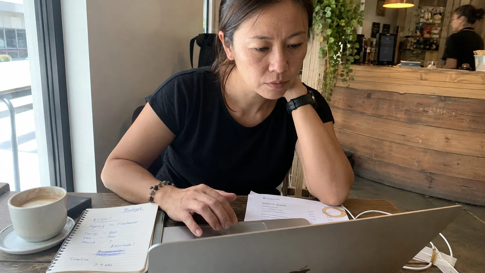 Singapore small business owner reviewing web design quotes and budget notes on a laptop