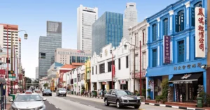 Row of colourful heritage shophouses on a Singapore street with office towers behind